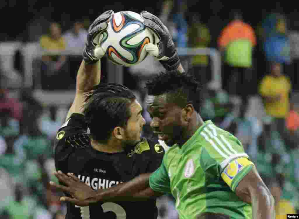 Iran's goalkeeper Alireza Haghighi (L) makes a save on Nigeria's Joseph Yobo during their 2014 World Cup Group F soccer match at the Baixada arena in Curitiba, June 16, 2014.