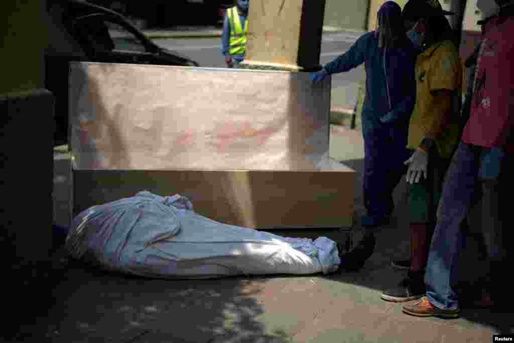 Empleados de una funeraria y familiares preparan un ataúd para el cuerpo de un hombre que había fallecido en su casa, en medio del brote del coronavirus en Guayaquil, Ecuador.