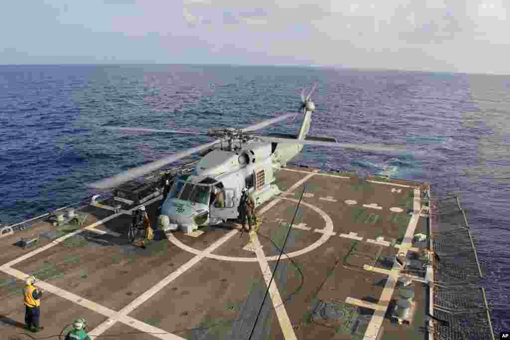 A U.S. Navy helicopter lands aboard Destroyer USS Pinckney during a crew swap before returning to a search and rescue mission for the missing Malaysian airlines flight MH370 in the Gulf of Thailand, March 9, 2014. 