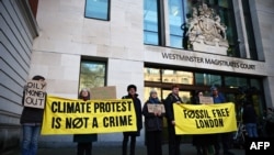 Manifestantes sostienen pancartas antes de la llegada de la activista ambiental sueca Greta Thunberg y otras cuatro personas al Tribunal de Magistrados de Westminster en Londres el 1 de febrero de 2024, para el primer día de juicio.
