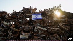 Izraelska zastava istaknuta na gomilu ugljenisanih vozila koja su bila spaljena tokom krvavog napada militanata Hamasa na Izrael 7. oktobra, ispred grada Netivota, južni Izrael, 7. anuara 2024. Vozila su sakuplena i poređana nedaleko od granice sa Gazom nakon napada.
