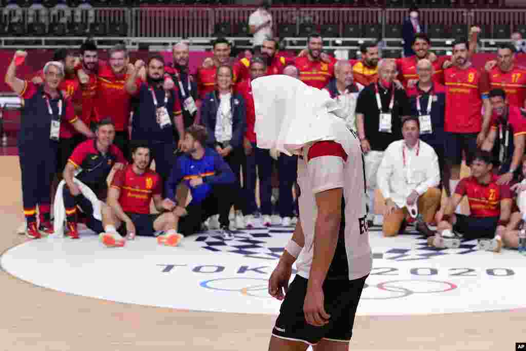 Egypt's Ahmed Mohamed, center, walks as Spain's team members celebrate after the men's bronze medal match handball match between Egypt and Spain at the 2020 Summer Olympics, Saturday, Aug. 7, 2021, in Tokyo, Japan. (AP Photo/Pavel Golovkin)