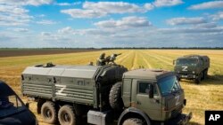 Уборка урожая зерновых под охраной российских военных на оккупированной украинской территории вблизи Мелитополя. Архивное фотою 14 июля 2022 г. (AP Photo, File)