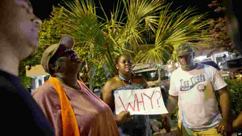 Surreace Cox, du nord de Charleston, en Caroline du Sud, tient une pancarte lors d'une veillée de prière sur la rue de l'église AME Emanuel jeudi matin 18 juin 2015 suite à une fusillade mercredi soir à Charleston.