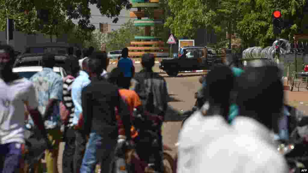 Les passants regardent une épaisse colonne de fumée noire au niveau de l'état-major des armées à Ouagadougou, Burkina Faso, le 2 mars 2018.