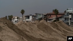 ARCHIVO - Casas frente al mar tapadas detrás de una montañas de arena reforzada como preparativos para enfrentar una tormenta en la playa de Long Beach, California, el 9 de septiembre de 2022.