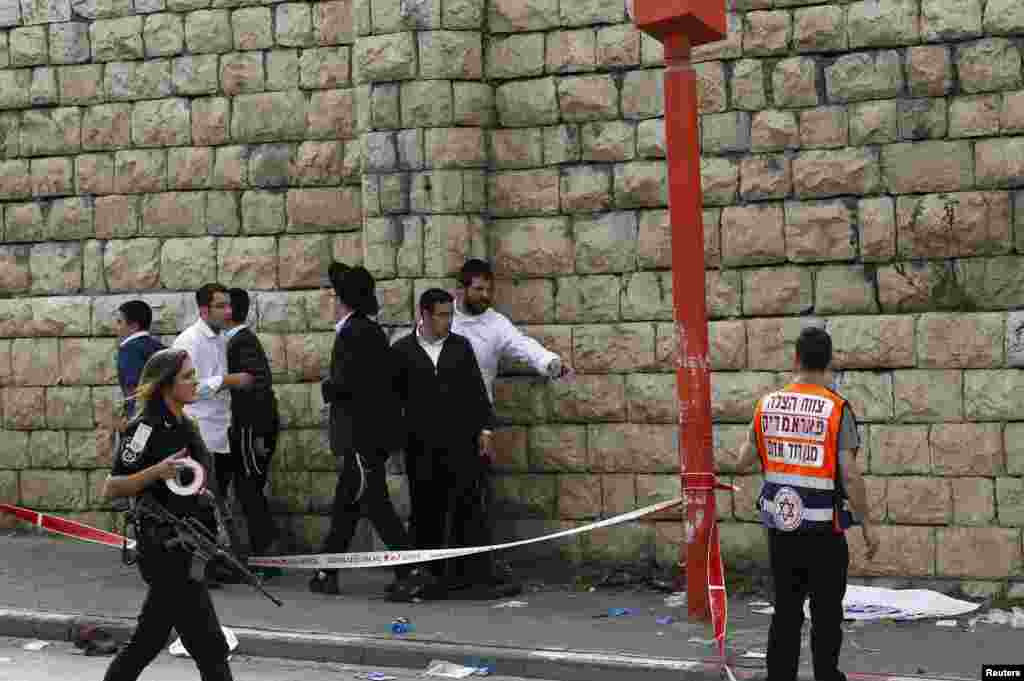 Passers-by stand at the scene of an attack in Jerusalem November 5, 2014. A motorist rammed into pedestrians on a crowded Jerusalem street and then got out of his vehicle to attack people with a metal bar on Wednesday in what Israeli police, who shot him