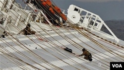 Dua orang anggota tim pertolongan Italia tengah bekerja di atas kapal Concordia (17/1). Upaya pertolongan dihentikan sementara, karena posisi kapal yang bergeser mempersulit upaya pencarian korban.