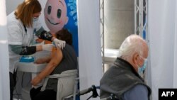 Una trabajadora de salud aplica una vacuna anti COVID-19 a una mujer israelí en Clalit Health Services, en la ciudad costera de Tel Aviv el 3 de enero de 2021. 