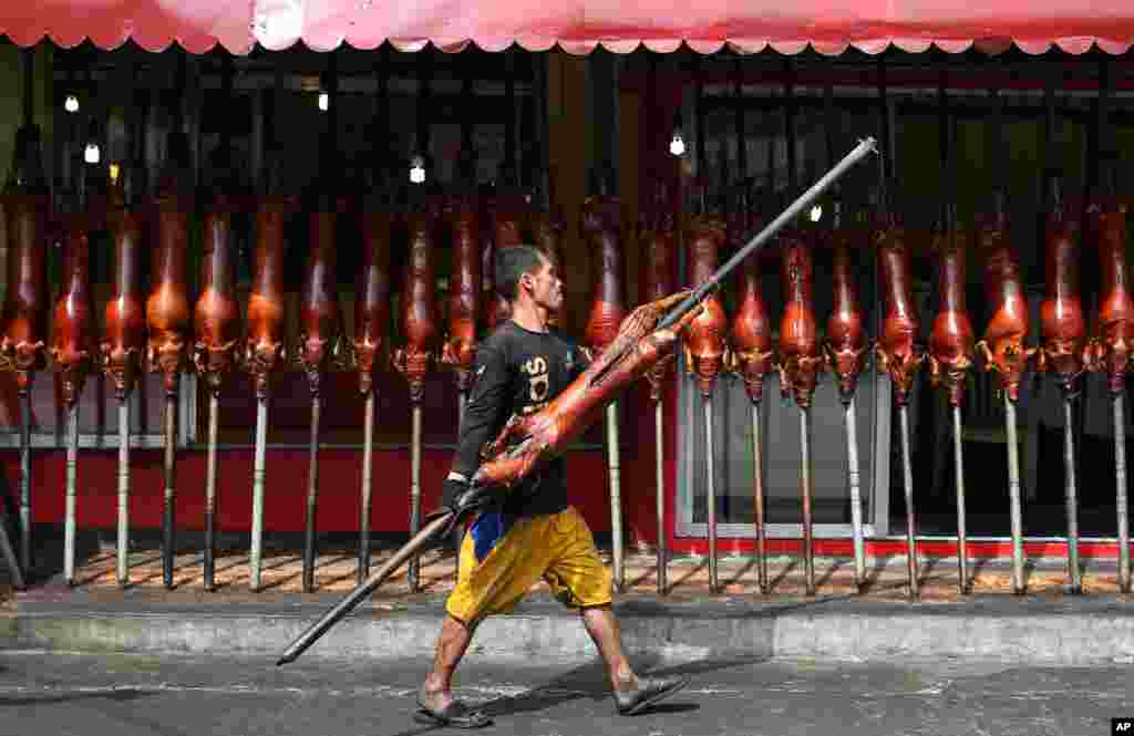 Seorang pekerja membawa babi panggang untuk dihidangkan pada jamuan Malam Natal di Quezon City, Filipina (24/12). (AP/Aaron Favila)