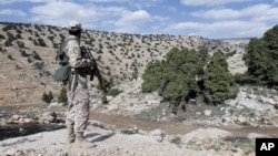 FILE - A Lebanon Hezbollah fighter carries his weapon as he stands in Khashaat, in the Qalamoun region.
