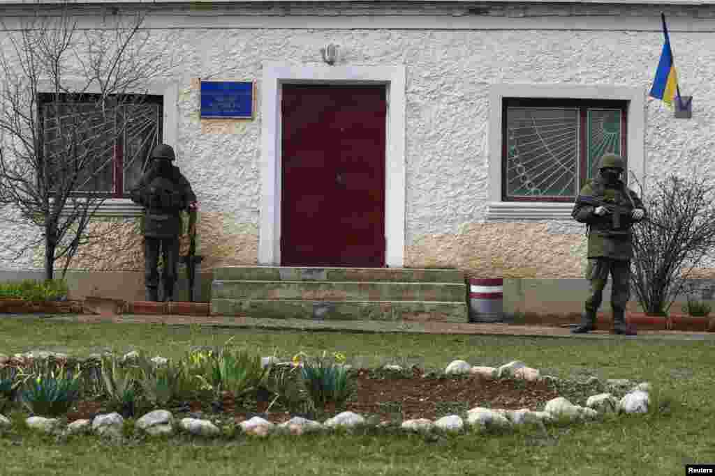Armed men, believed to be Russian servicemen, stand guard outside an entry to a Ukrainian military base in the village of Perevalnoye near the Crimean city of Simferopol, March 9, 2014. 