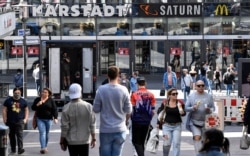People walk to a shopping center as many smaller stores are allowed to open in Essen, Germany, April 20, 2020.