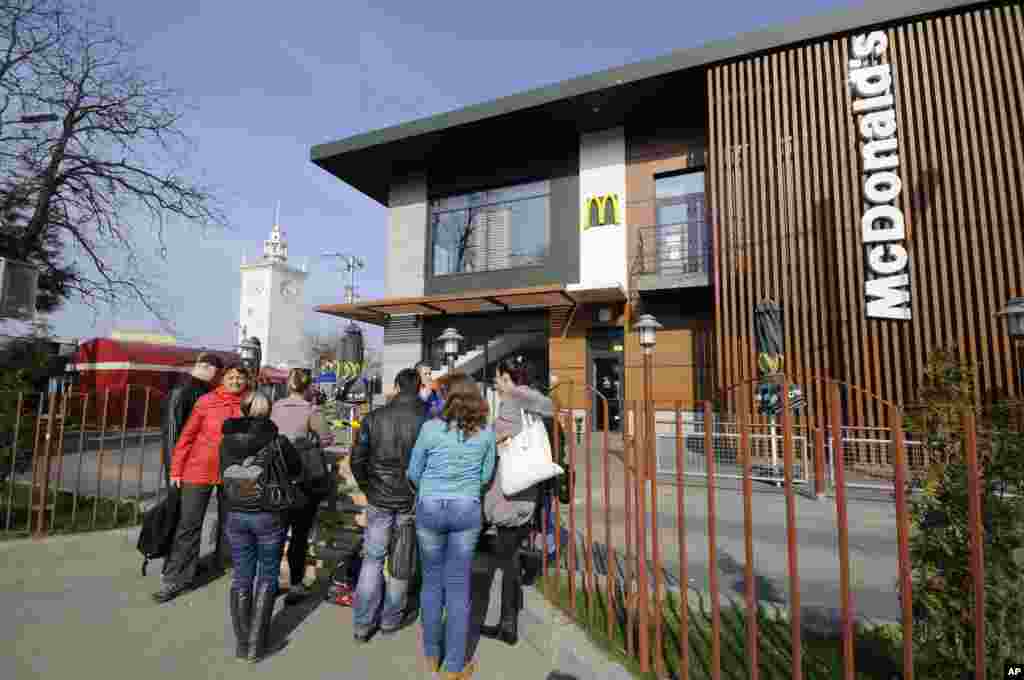 People stand outside a closed McDonalds restaurant. The fast food restaurant chain announced this week that it is shuttering its three outlets in the Crimean peninsula over unspecified operations issues, Simferopol, Crimea, April 4, 2004.