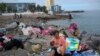 ARCHIVO - Una migrante venezolana amamanta a su hijo luego de que la policía les dijera que desmantelaran el campamento a la orilla del mar donde vivía con su familia en El Morro, un barrio de Iquique, Chile, el domingo 12 de diciembre de 2021.