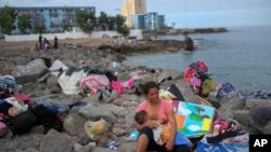 ARCHIVO - Una migrante venezolana amamanta a su hijo luego de que la policía les dijera que desmantelaran el campamento a la orilla del mar donde vivía con su familia en El Morro, un barrio de Iquique, Chile, el domingo 12 de diciembre de 2021.