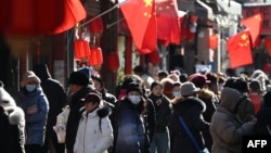 资料照片: 2025年2月3日北京购物街附近小巷里的行人。