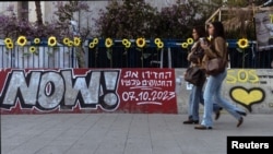 Mujeres caminan junto a un graffiti que apoya la liberación de los rehenes que han sido retenidos en Gaza desde el mortal ataque del 7 de octubre de 2023, en Tel Aviv, Israel, el 18 de febrero de 2025. 