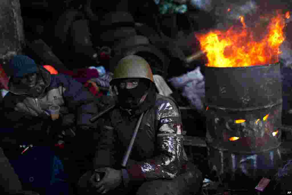 An opposition supporter looks on as he warms himself next to a fire in a barricade near Kyiv's Independence Square, Jan. 31, 2014.