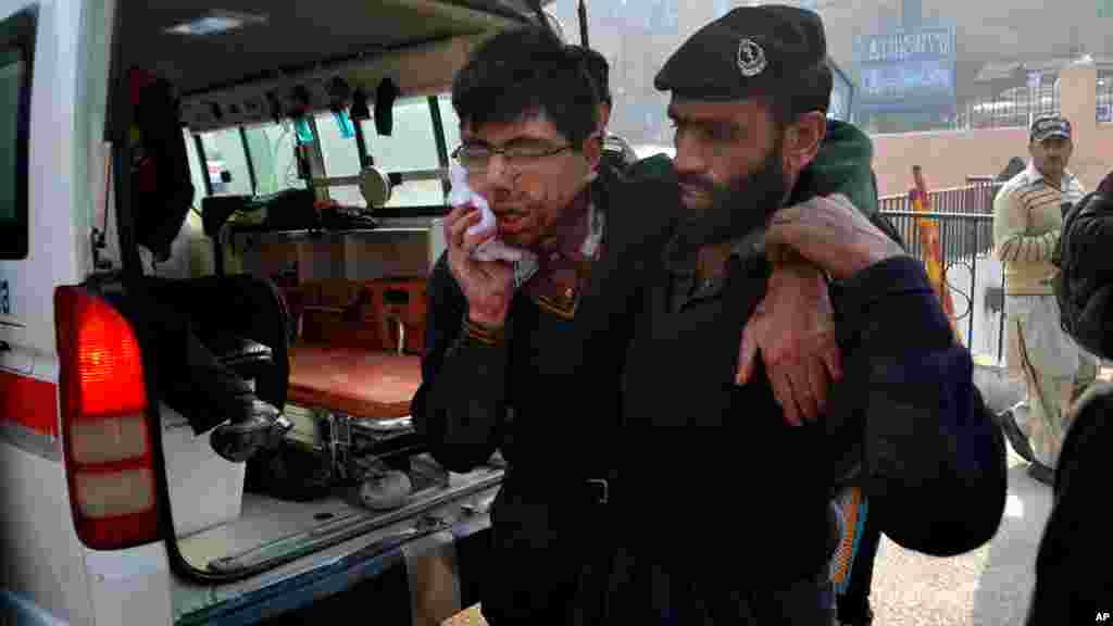 Un garde de sécurité de l'hôpital aide un étudiant blessé dans la fusillade dans une école sous l'attaque par des hommes armés talibans à Peshawar, au Pakistan, le mardi 16 décembre 2014.