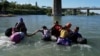 Migrantes cruzan el Río Grande en medio de fuertes corrientes provenientes de México en Eagle Pass, Texas, EEUU, el 29 de septiembre de 2023.