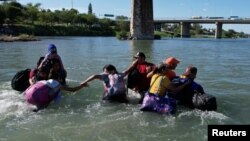 Migrantes cruzan el Río Grande en medio de fuertes corrientes provenientes de México en Eagle Pass, Texas, EEUU, el 29 de septiembre de 2023.