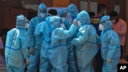 Health workers and volunteers in personal protective suits wait to receive patients outside a COVID-19 hospital that was set up at a Sikh Gurdwara in New Delhi, India, Monday, May 10, 2021. (AP Photo/Ishant Chauhan)