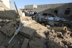 FILE - People stand at the site of a Houthi ballistic missile attack over the populated district of Rawda in Marib, Yemen, Feb. 6, 2020.