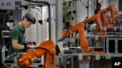 Seorang pekerja tengah bekerja di antara tangan-tangan robot di pabrik Rapoo Technology di kawasan industri Shenzhen, China (Foto: dok). 