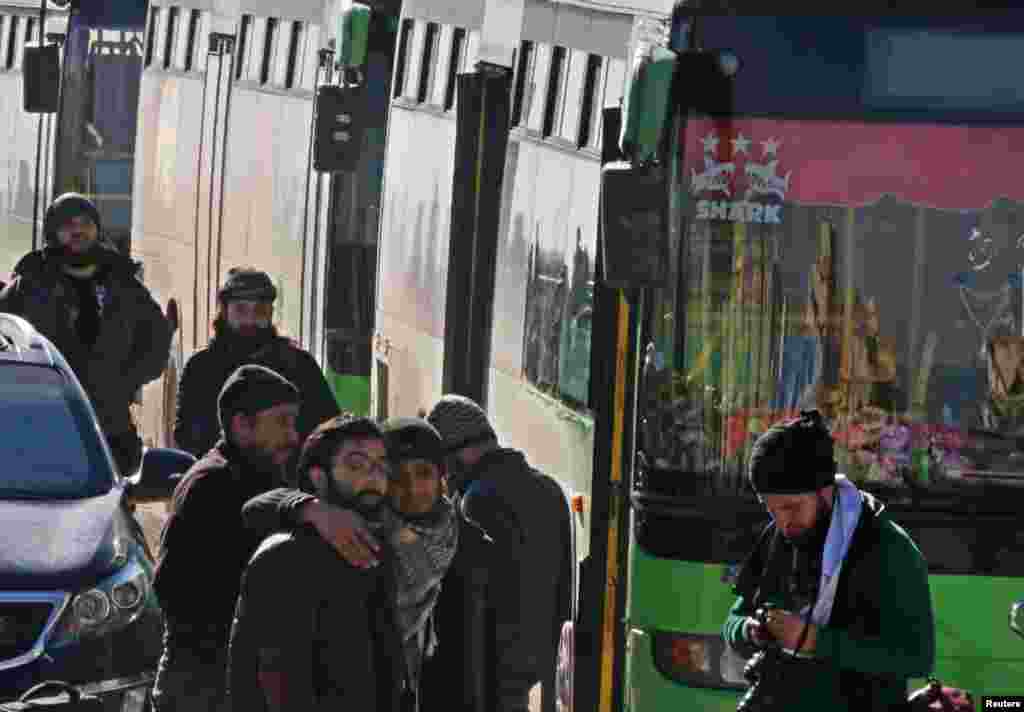 Men react as they stand outside buses evacuating people from a rebel-held sector of eastern Aleppo, Syria Dec. 15, 2016.