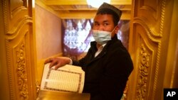 资料照：在政府组织的外国记者访问中国新疆一名维吾尔族男子阿克苏的家中时，他拿着一本阿拉伯语和维吾尔语的《古兰经》。(2021年4月20日)