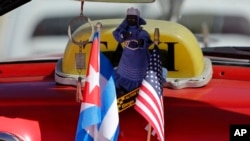 The stars and stripes and the Cuban national flag are placed together on the dashboard of a vintage American convertible in Havana, Cuba, Feb. 18, 2016.