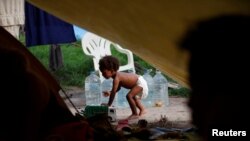 El solicitante de asilo Natanael, de 1 año, cuya madre es venezolana pero nació en Colombia, juega con un carrito de juguete junto a su tienda de campaña en un campamento improvisado, en Matamoros, México 20 de junio de 2023