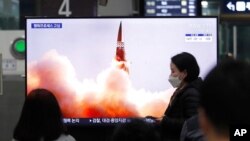 Arhiva - Ljudi gledaju TV program na kome se vidi fotografija severnokorejske nove vodeće rakete, tokom emisije vesti, na železničkoj stanici u Seulu, Južna Koreja, 26. marta 2021.