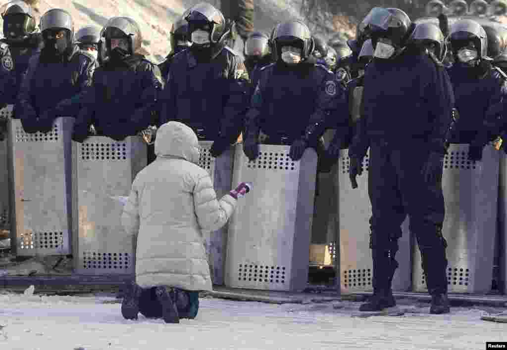 A woman kneels as she appeals to Ukrainian police troops at the site of clashes with anti-government protesters in Kyiv. Protesters erected more street barricades and occupied a government ministry building on Friday after the failure of crisis talks.