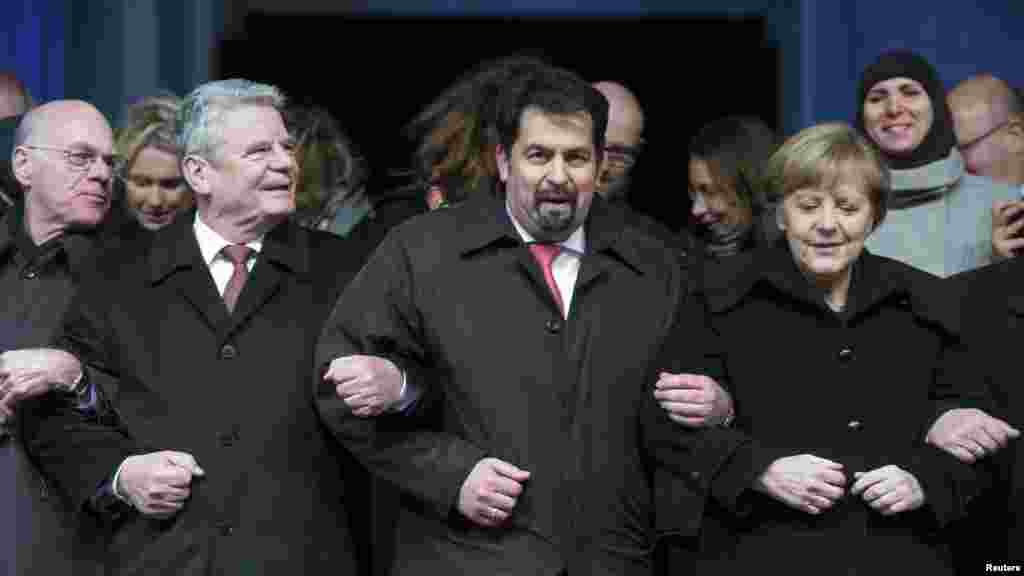 Le président du Bundestag, Norbert Lammert, le président allemand Joachim Gauck, le président du Conseil central des musulmans en Allemagne Aiman Mazyek et la chancelière allemande Angela Merkel, mrachent, bras dans le bras, lors d'une veillée organisée pour les victimes de la fusillade.