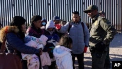 Migrantes conversan con un miembro de la Patrulla Fronteriza de EEUU, el martes 5 de diciembre de 2023 en Lukeville, Arizona.
