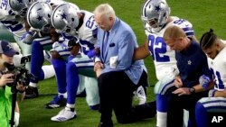 El dueño de los Cowboys, Jerry Jones (centro) hincado junto con los jugadores antes del himno nacional, en Glendale, Arizona.