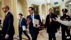 Treasury Secretary Steven Mnuchin, third from left, and White House Legislative Affairs Director Eric Ueland, left, walk to a meeting with Senate Minority Leader Sen. Chuck Schumer of N.Y. in his office on Capitol Hill, March 23, 2020. 
