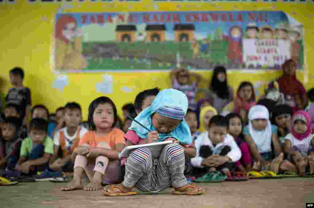 Johainah Nasrodeng, 5, writes in her notebook at a makeshift classroom at the Pantar Central Elementary School in Pantar, Lanao del Norte on the southern island of Mindanao, Philippines. The schoolchildren, some 238 of them with their parents fled by foot for eight hours from Marawi City to Pantar municipality to escape heavy fighting between the government troops and Islamists militants.
