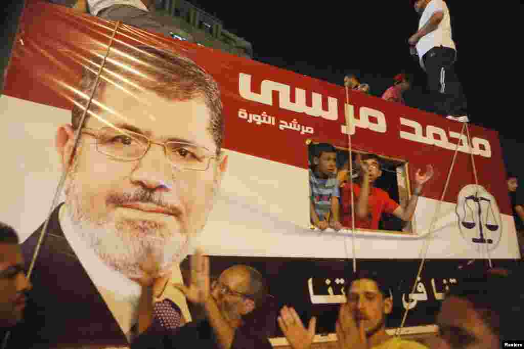 Tahrir maydonida prezident Muhammad Mursiyning tasvirini ko'targan odamlar, Qohira, Misr, 10-iyul, 2012-yil.