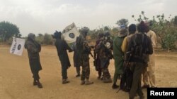 Des combattants de Boko Haram (en camouflage) s'embrassent et se serrent la main avec les prisonniers de Boko Haram, libérés en échange d'un groupe de 82 filles Chibok, près de Kumshe, Nigeria, 6 mai 2017.