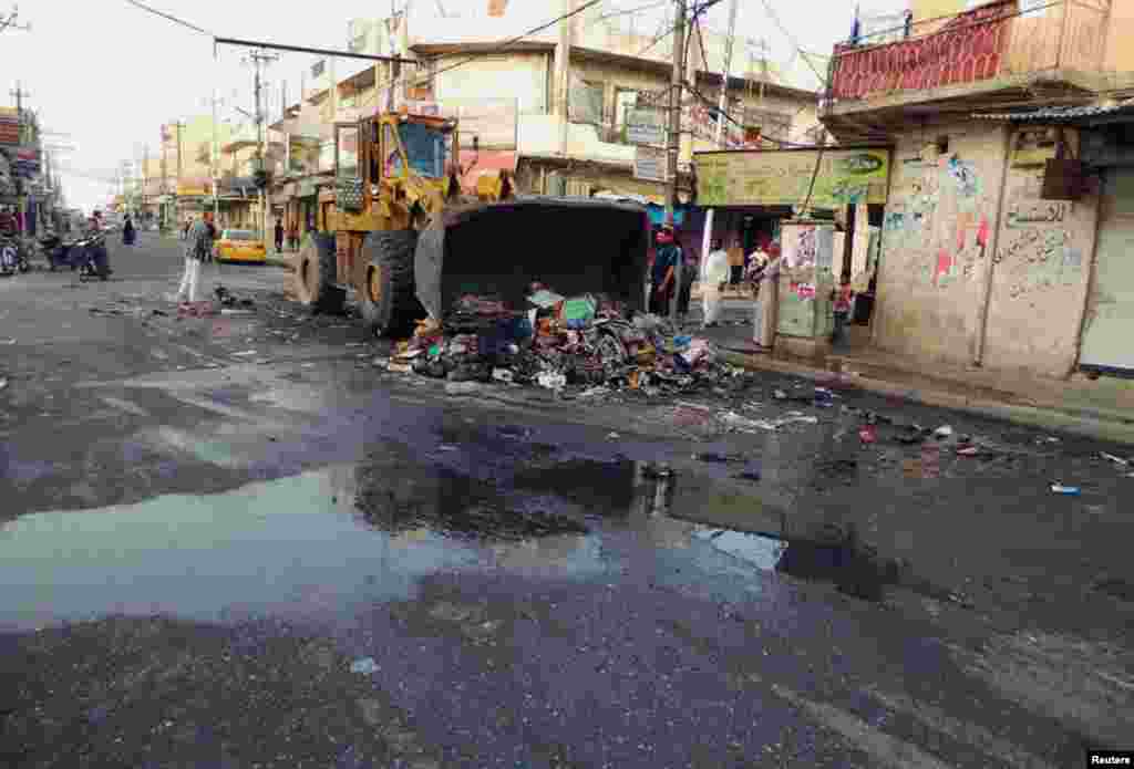People clean a street now under militant control, in the northern city of Mosul, June 13, 2014. 