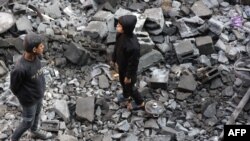 2025年1月1日，巴勒斯坦儿童在加沙地带杰巴利耶前一天晚上遭到以色列袭击的现场观察损坏的情况。