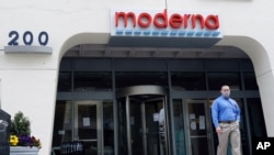 A man stands outside an entrance to a Moderna, Inc., building, May 18, 2020, in Cambridge, Mass.