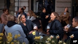 Orang-orang mengobrol dan minum di luar bar di Stockholm, Swedia. Swedia memberlakukan kebijakan yang relatif liberal untuk memerangi pandemi corona meskipun telah terjadi lonjakan tajam dalam kematian, 8 April 2020. (Foto: AP)