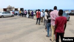 FILE - Migrants queue to receive food aid distributed by UNHCR, in Tripoli, Libya, May 12, 2020.
