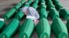 Devojka pregleda sanduk pripremljen za sahranu, u Potočarima, u blizini Srebrenice, Bosna i Hercegovina, 10. jula 2019.