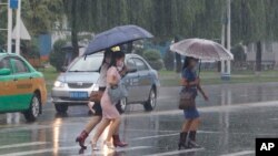 Women walk with umbrellas during torrential rains, August 5, 2020, in Pyongyang.