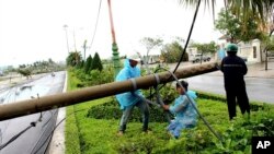 Para pekerja memperbaiki tiang listrik yang roboh akibat hantaman topan Damrey di provinsi Phu Yen, Vietnam, Sabtu, 4 November 2017. 